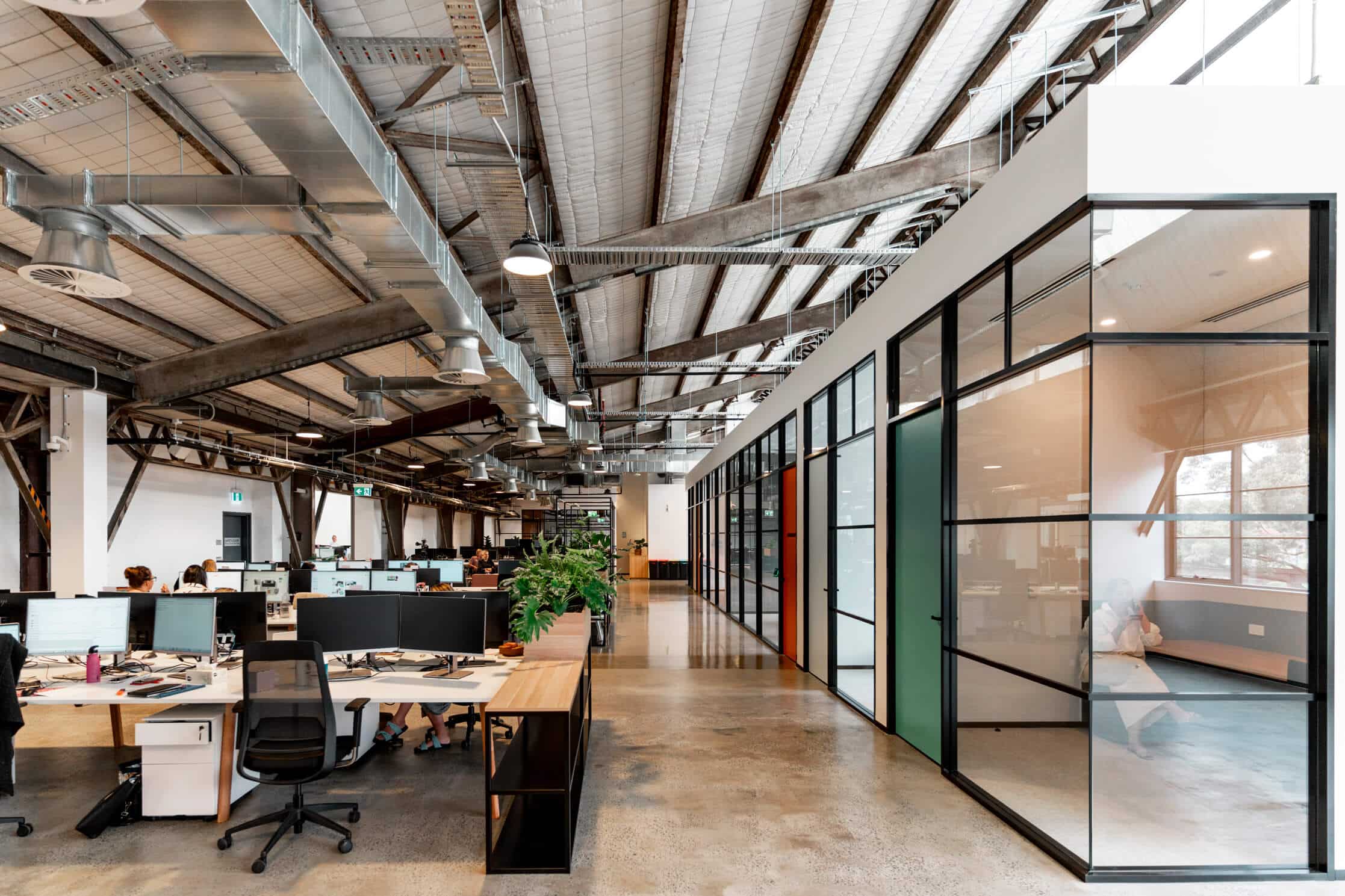 Modern office with multiple workstations, stylish chairs, and sleek desks, featuring an open layout with ample natural light.