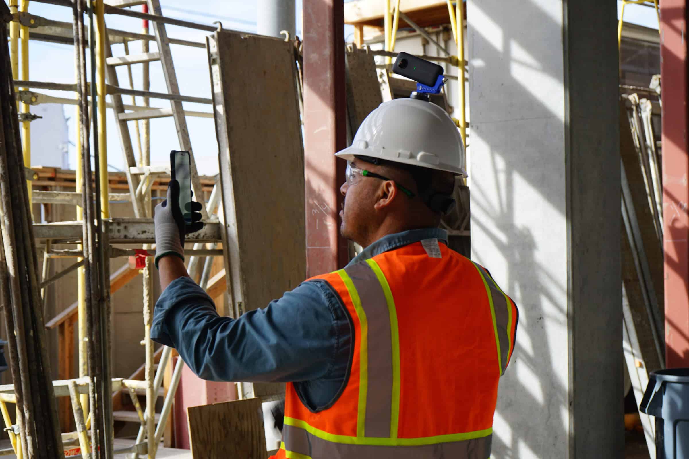 Individual taking image on iPhone while on a construction site wearing construction gear.