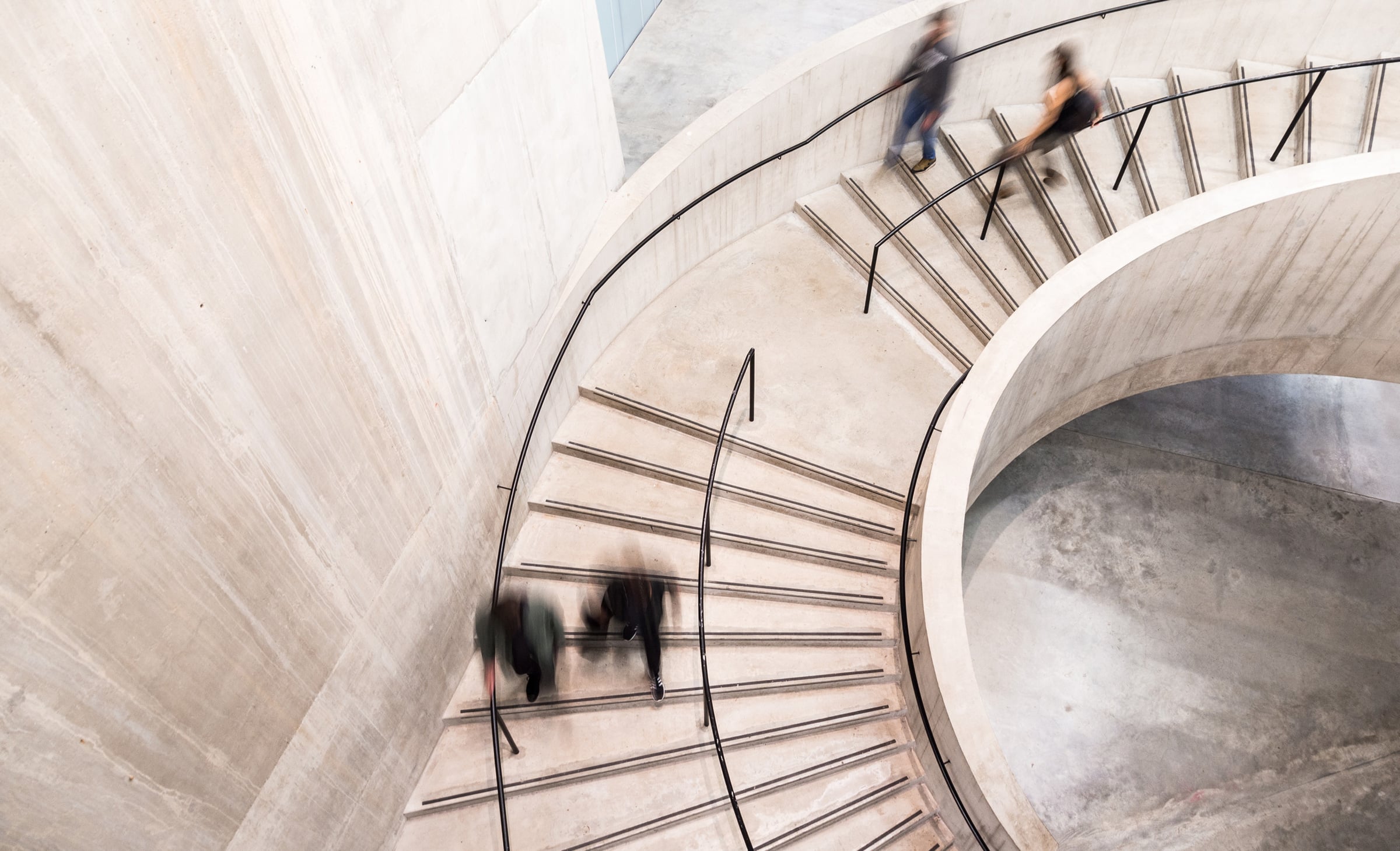 Four people walking down spiral staircase in blurred motion.