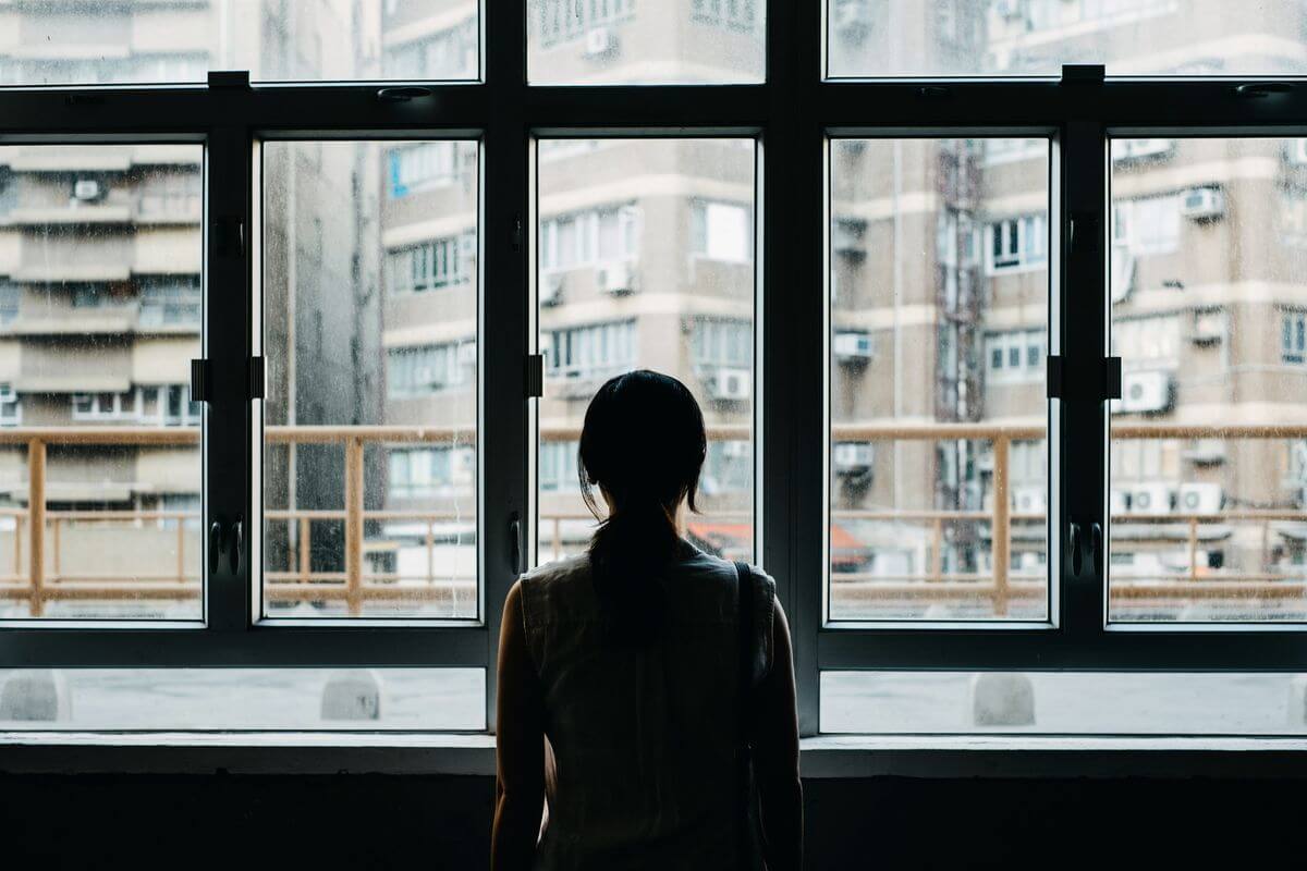 Woman looking out window to city landlscape.