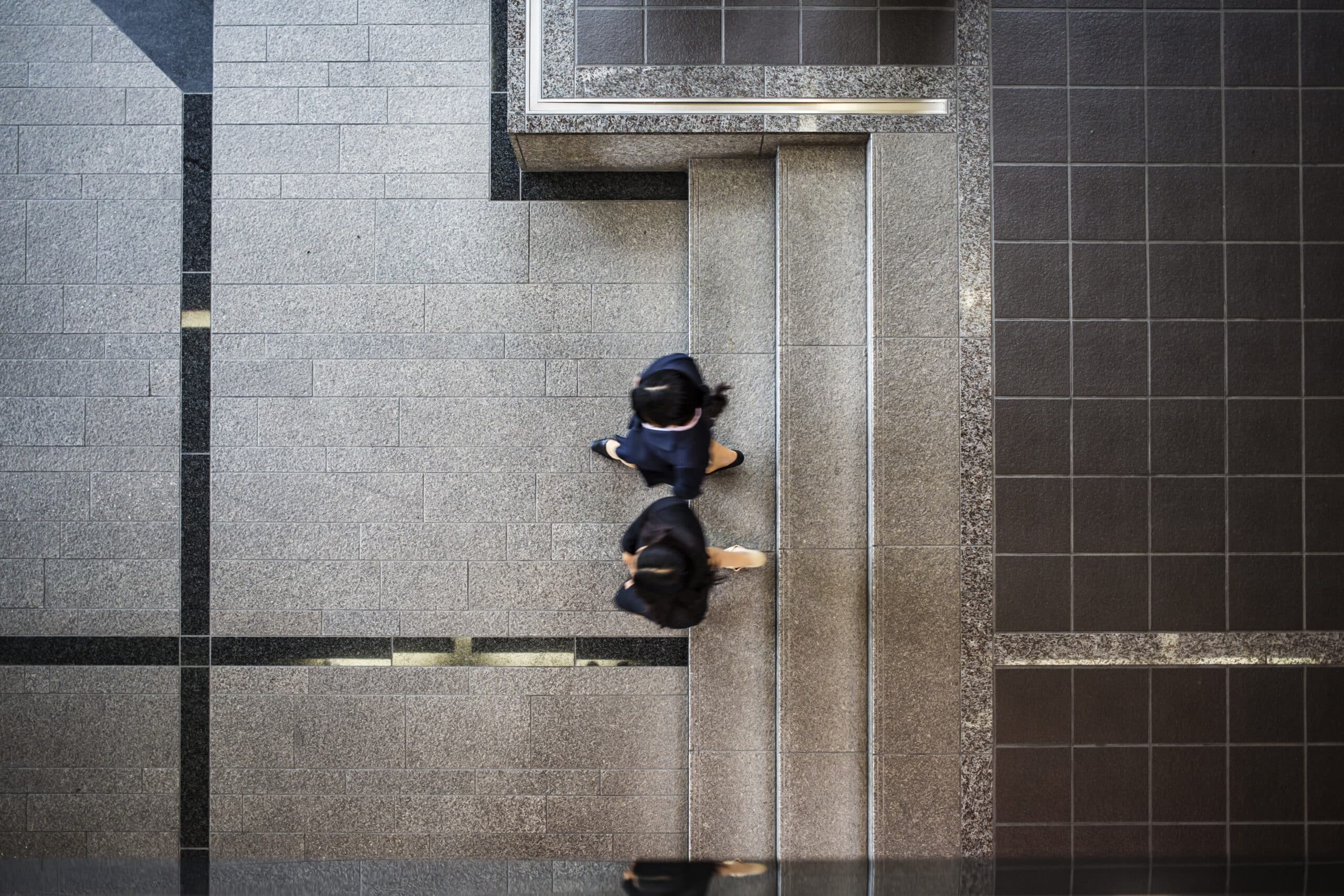 Aerial view of business women entering and meeting in the lobby of modern office building.