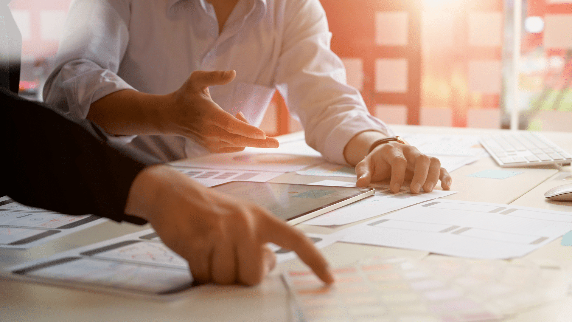 Close up of two people in a meeting setting discussing plans on paper and a screen