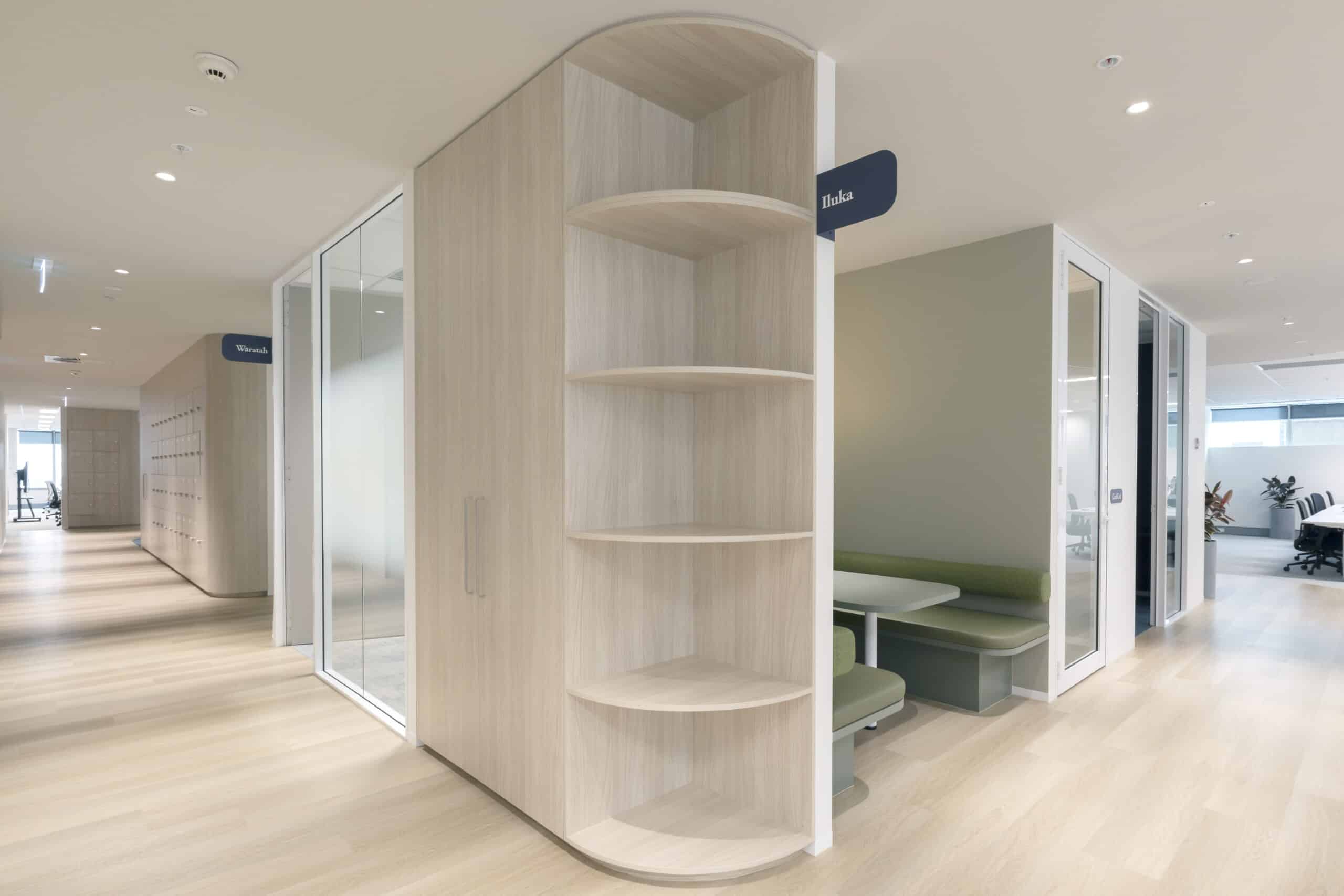 Contemporary office space with several shelves, desk and areas for collaboration including meeting rooms and booths.