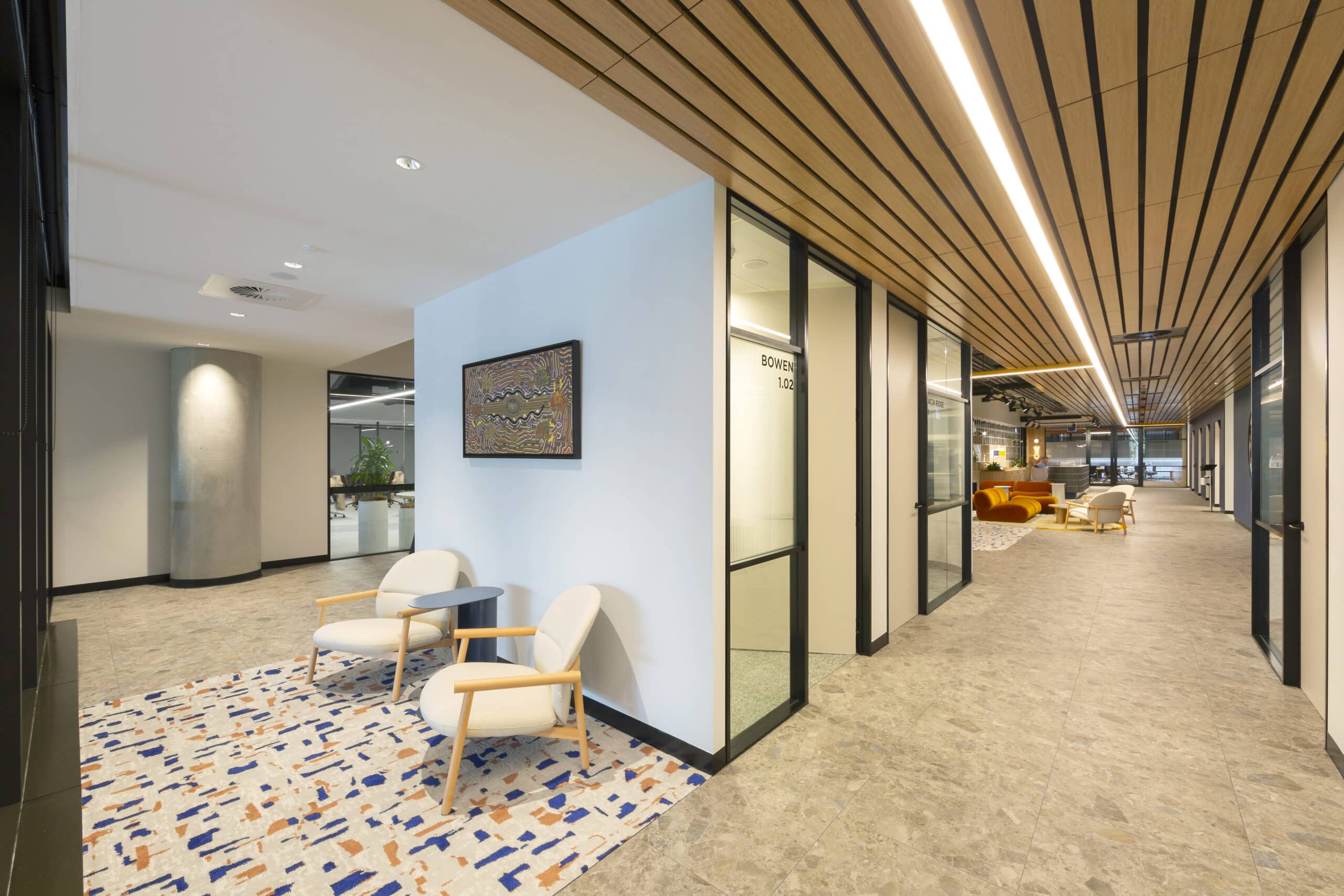 Modern office with multiple workstations, stylish chairs, and sleek desks, featuring an open layout with ample natural light.