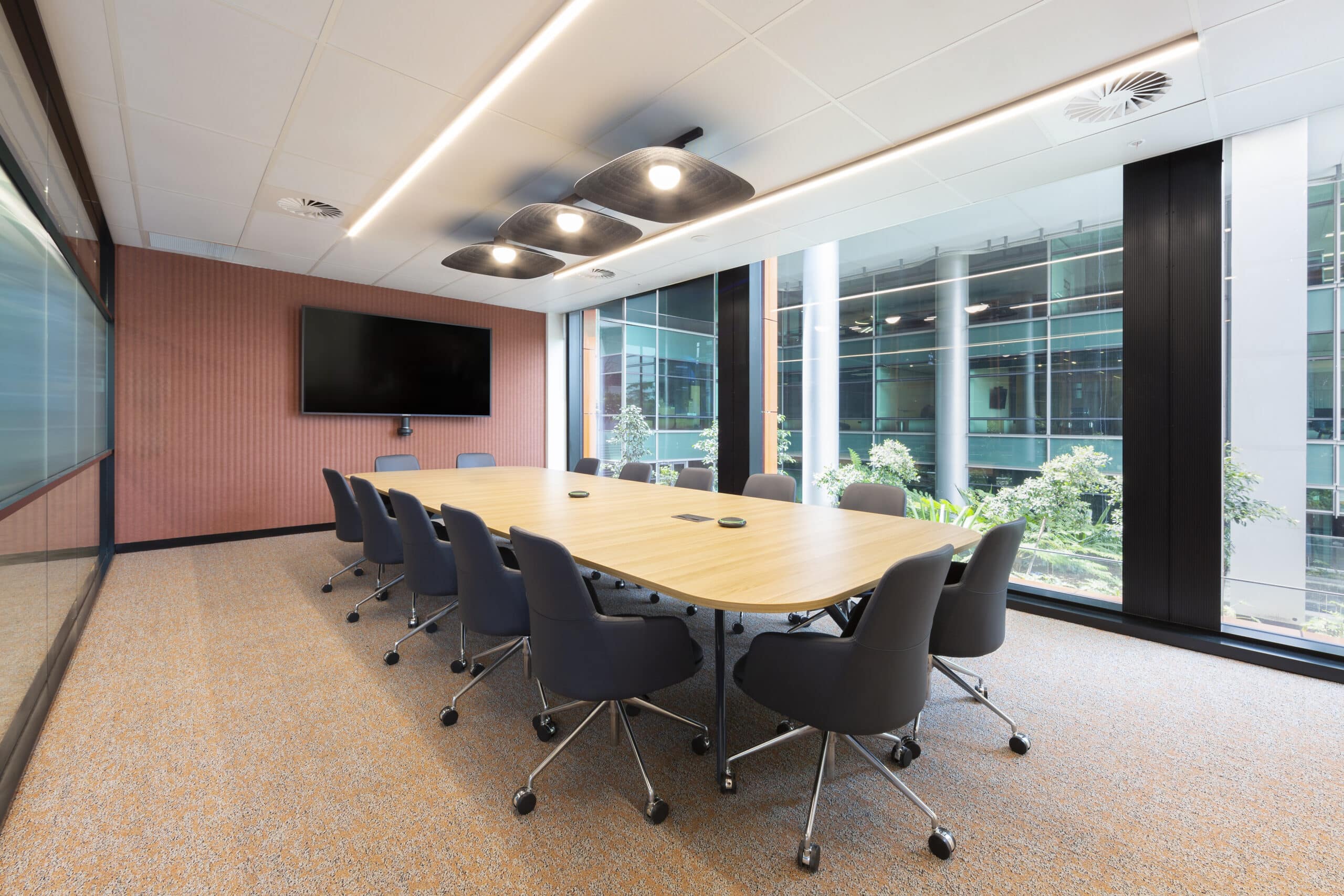 Professional meeting room with a spacious table, ergonomic chairs, and large windows, designed for collaboration in a professional setting.